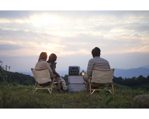 Szene mit Familie beim Camping mit tragbarer Powerstation und Campingmöbeln