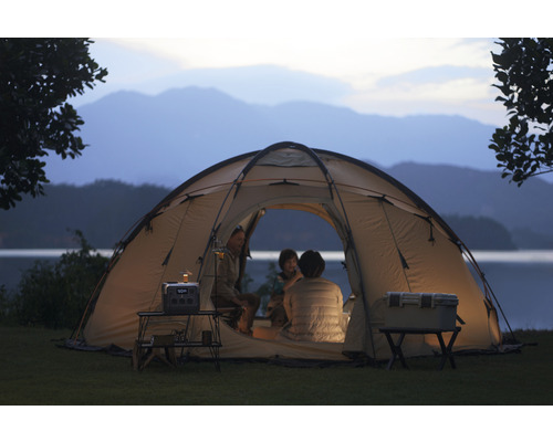 Szene mit Campingzelt, Kühlbox, Tisch und tragbarer Powerstation in der Natur