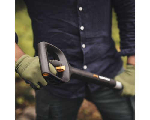 Eine Person hält einen schwarzen Fiskars Spaten mit Griff und Blatt in der Hand, während sie Handschuhe trägt.