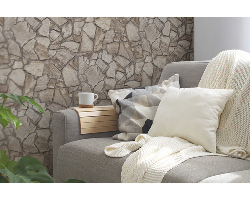 Wohnzimmer mit Steinwand, Couch, Kissen, Decke und Tasse