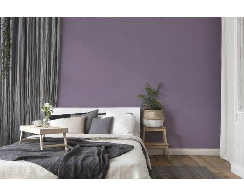 Schlafzimmer mit Bett, Holzboden und lila Wand