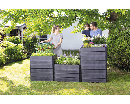 Familie bepflanzt Hochbeete aus Holz im Garten