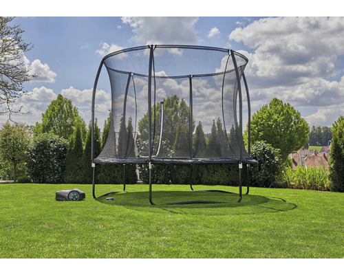 Trampoline avec filet de sécurité et robot tondeuse dans le jardin.