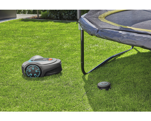 Robot tondeuse Gardena avec station de charge sur pelouse sous un trampoline