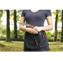 Une femme tient une scie à main devant un tablier de jardinage