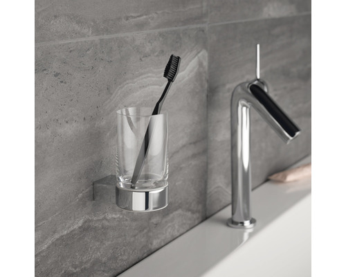Glaszahnbürstenhalter mit Zahnbürste und Wasserhahn im Badezimmer