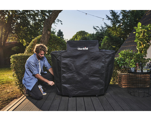 Un homme fixe une housse de barbecue Char-Broil sur une terrasse