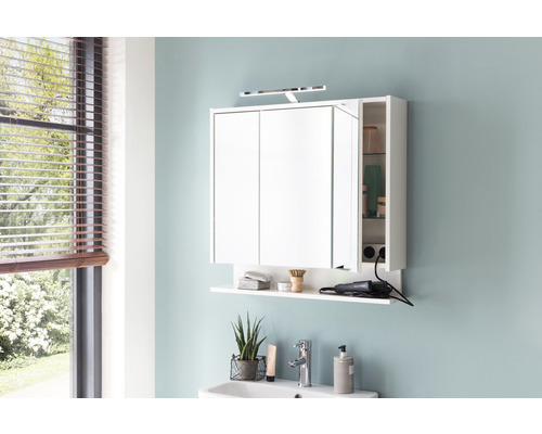 Salle de bains moderne avec armoire de toilette blanche à miroir, étagère et éclairage au-dessus d''un lavabo.