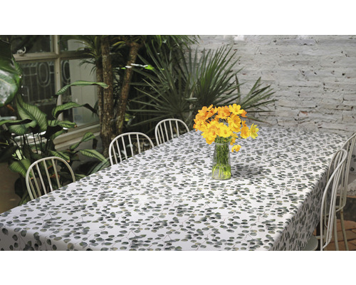 Tisch mit blättergemusterter Tischdecke und gelben Blumen in einer Vase
