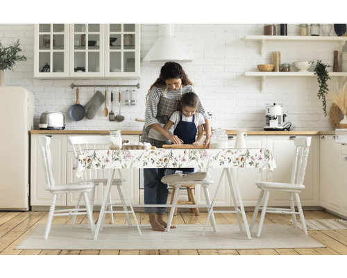 Helle Küche mit Mutter und Kind beim Backen am Tisch mit Tischdecke mit Blumenmuster