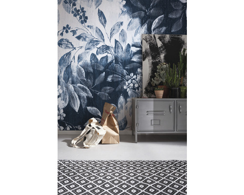 Vue d''une pièce avec papier peint fleuri, armoire en métal, tableau, plantes d''intérieur et tapis à motifs géométriques