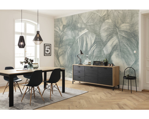 Salle à manger avec table à manger, chaises, buffet et papier peint à motifs de feuilles pour une atmosphère lumineuse et organisée.