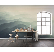 Ein Zimmer mit einer Fototapete, die eine Berglandschaft darstellt, einem Schreibtisch, einem Stuhl und einem Fenster.