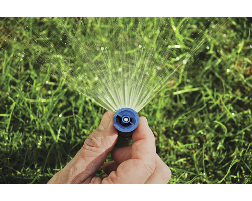 Eine Hand hält einen Rasensprenger, der Wasser sprüht