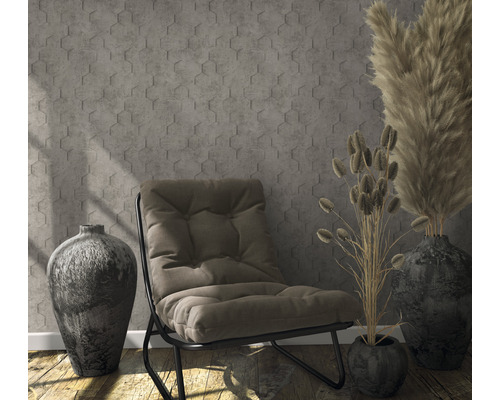 Szene mit Sessel, Vasen und dekorativen Gräsern vor einer Wand mit sechseckigem Muster.