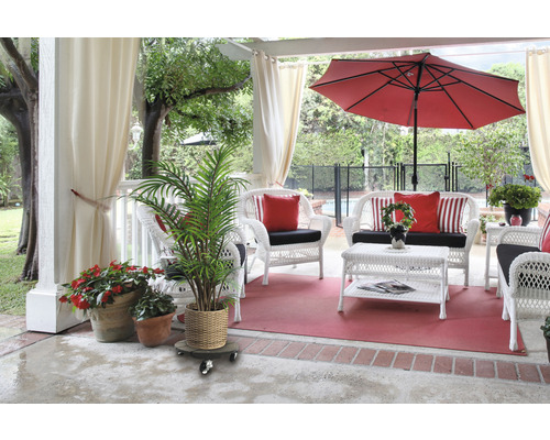 Terrasse avec mobilier en rotin blanc, parasol rouge et plantes en pot