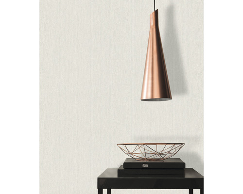 Nahaufnahme einer Wand mit Textiltapete, kombiniert mit einer Hängelampe und dekorativen Elementen auf einem Tisch