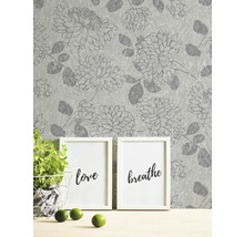 Papier peint à motif floral, deux cadres, plante en pot et citrons verts sur une table