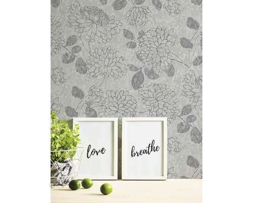 Tapete mit Blumenmuster, zwei Bilderrahmen, Topfpflanze und Limetten auf einem Tisch