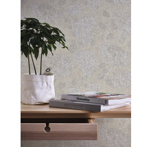 Szene mit einer beigen Tapete mit Blumenmuster, einem Holztisch mit einer Pflanze und Büchern