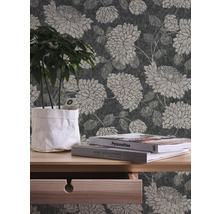 Innenraumszene mit floral gemusterter Tapete, Holztisch mit Pflanze und Büchern