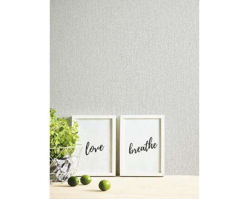 Tapete mit zwei Bilderrahmen, Topf mit Pflanze und Limetten auf einem Tisch