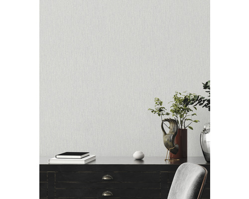 Dekoratives Interieur mit strukturierten Tapeten an der Wand, Bücher auf einem dunklen Sideboard mit Topfpflanze und Dekorationen