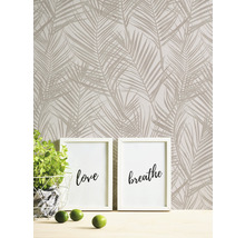 Mur avec papier peint à motifs de palmiers, deux cadres photo avec les inscriptions amour et respirer