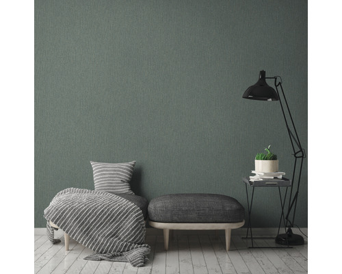 Wohnzimmer mit grauer Textiltapete, Sessel, Hocker und Stehlampe