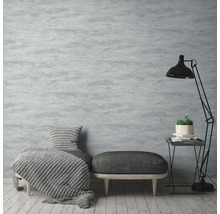 Wohnzimmer mit grauer gemusterter Tapete, Sessel, Hocker und Stehlampe