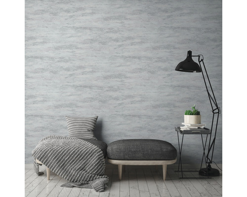 Wohnzimmer mit grauer gemusterter Tapete, Sessel, Hocker und Stehlampe