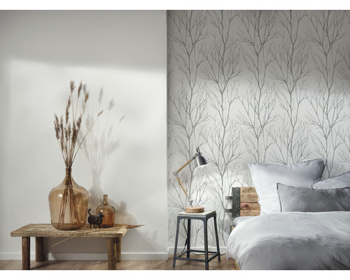 Ein Schlafzimmer mit einem Bett, einem Nachttisch und einer Wand mit Baumtapete.