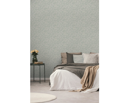 Schlafzimmer mit gemusterter Tapete, Bett und Beistelltisch mit Blumen