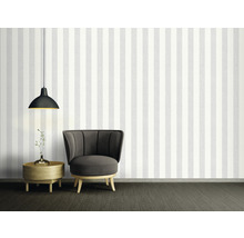 Dekoratives Zimmer mit Streifentapete, Sessel, Lampe und Beistelltisch