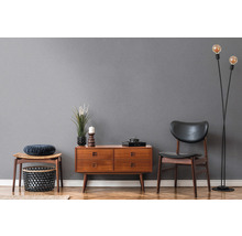 Wohnzimmer mit Holzkommode, Stuhl, Hocker und Stehlampe