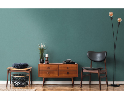 Intérieur de salon avec commode en bois, chaise, lampadaire et décoration sur parquet devant un mur coloré