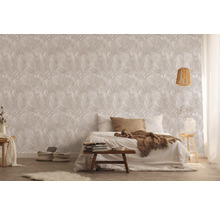 Chambre avec lit devant un mur avec du papier peint à motifs de feuilles.
