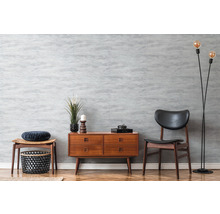 Wohnraum mit Kommode, Stuhl und Stehlampe im Retro-Stil vor grauer Wand