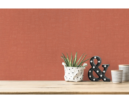 Nahaufnahme einer Wand mit Textiltapete, Zimmerpflanze, Deko-Buchstaben und Keramikbechern auf einem Tisch