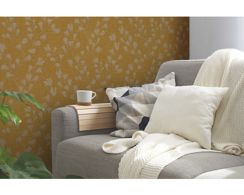 Wohnzimmer mit gemusterter Tapete, Sofa, Kissen, Decke und Pflanze