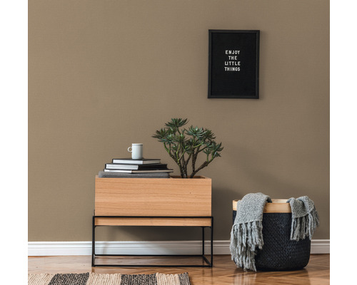 Dekoratives Interieur mit Holztisch, Pflanze, Büchern, Tasse und Korb mit Decke