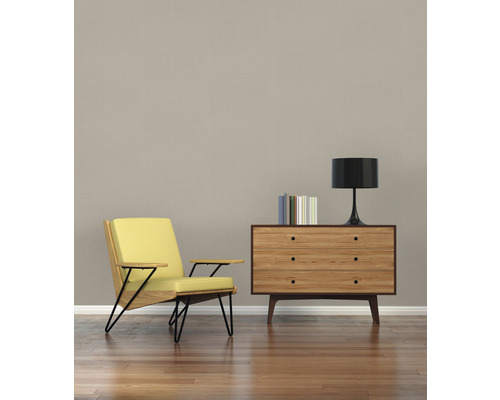 Wohnzimmer mit Sessel, Holzkommode, Lampe und Büchern