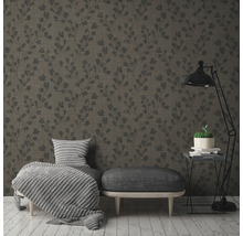 Ein Wohnzimmer mit einer gemusterten Tapete, einem Hocker, einem Sessel und einer Stehlampe.