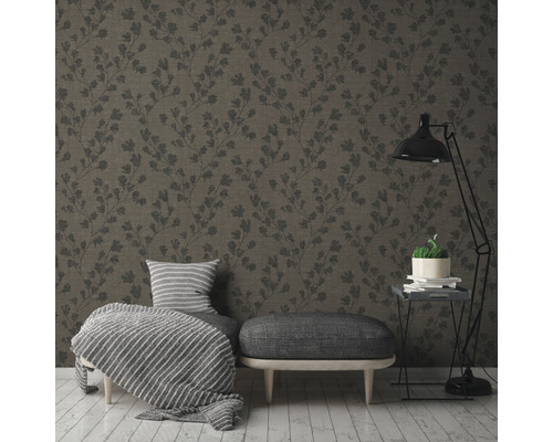 Ein Wohnzimmer mit einer gemusterten Tapete, einem Hocker, einem Sessel und einer Stehlampe.