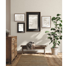 Wohnzimmer mit Kommode, Bank, Zimmerpflanze, Teppich und Bildern an der strukturierten Tapetenwand