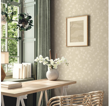 Ein Zimmer mit einem Schreibtisch, einer Vase mit Blumen, einem Bild an der Wand und einer gemusterten Tapete