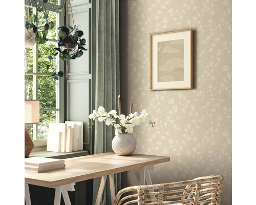 Une pièce avec un bureau, un vase de fleurs, un tableau au mur et un papier peint à motifs