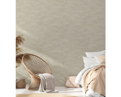 Chambre avec fauteuil en rotin, lit et papier peint à motifs pour une ambiance claire et conviviale.
