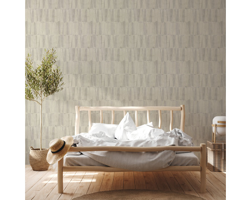 Schlafzimmer mit Bett vor einer Wand mit gemusterter Tapete und einer Topfpflanze.