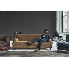 Wohnzimmer-Szene mit Sofa, Sessel, Hocker und stilvoll gekleidetem Mann